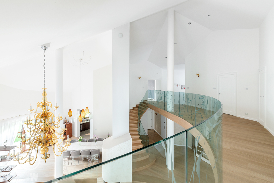 Fotografia wnętrza domu zaprojektowanego przez biuro projektowe, antresola widoczne duże żyrandole w salonie i jadalni.