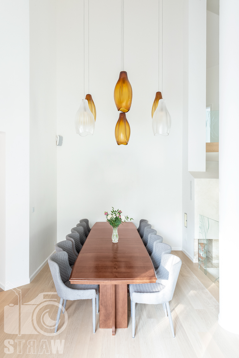 Fotografia wnętrz domu zaprojektowanego przez biuro projektowe, jadalnia i wiszące lampy nad stołem.
