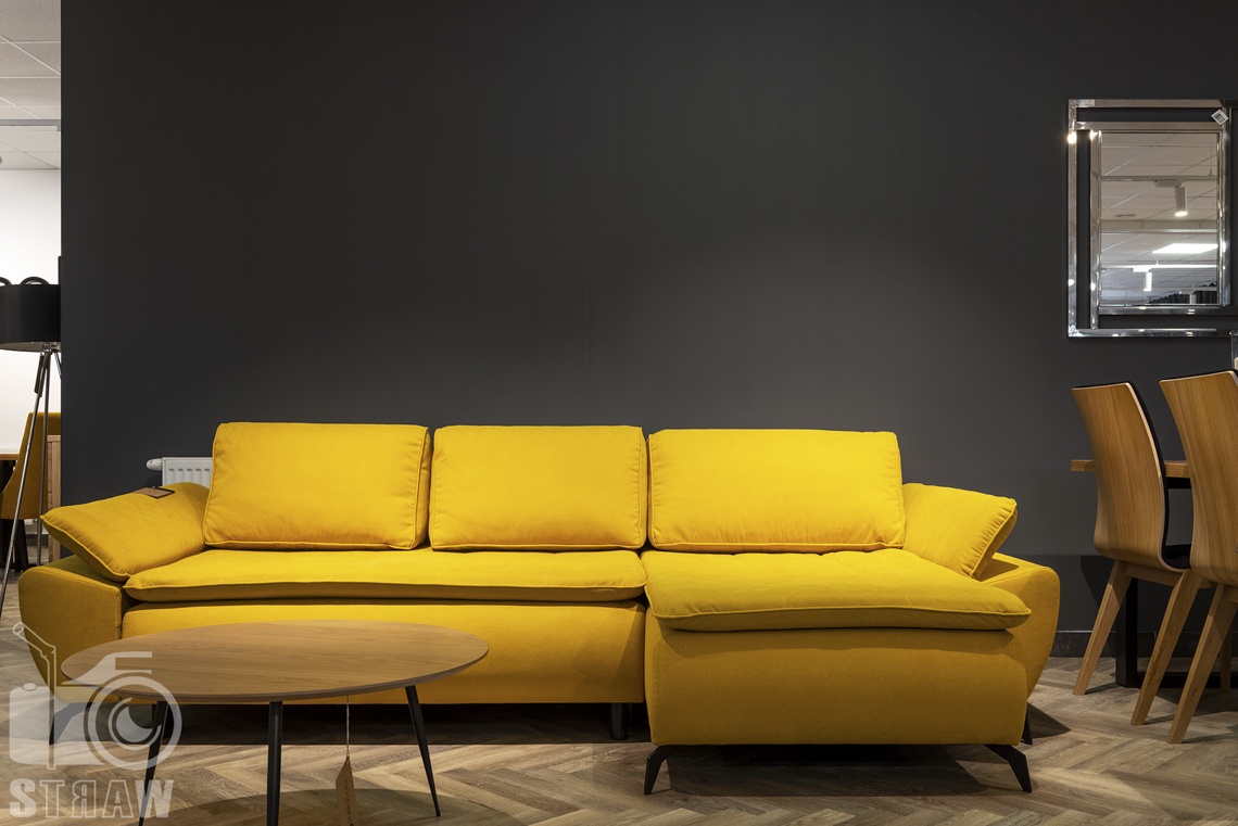 Fotografia wnętrz komercyjnych, zdjęcia showroomu meblowego, na zdjęciu żółta sofa i okrągły drewniany stolik kawowy.